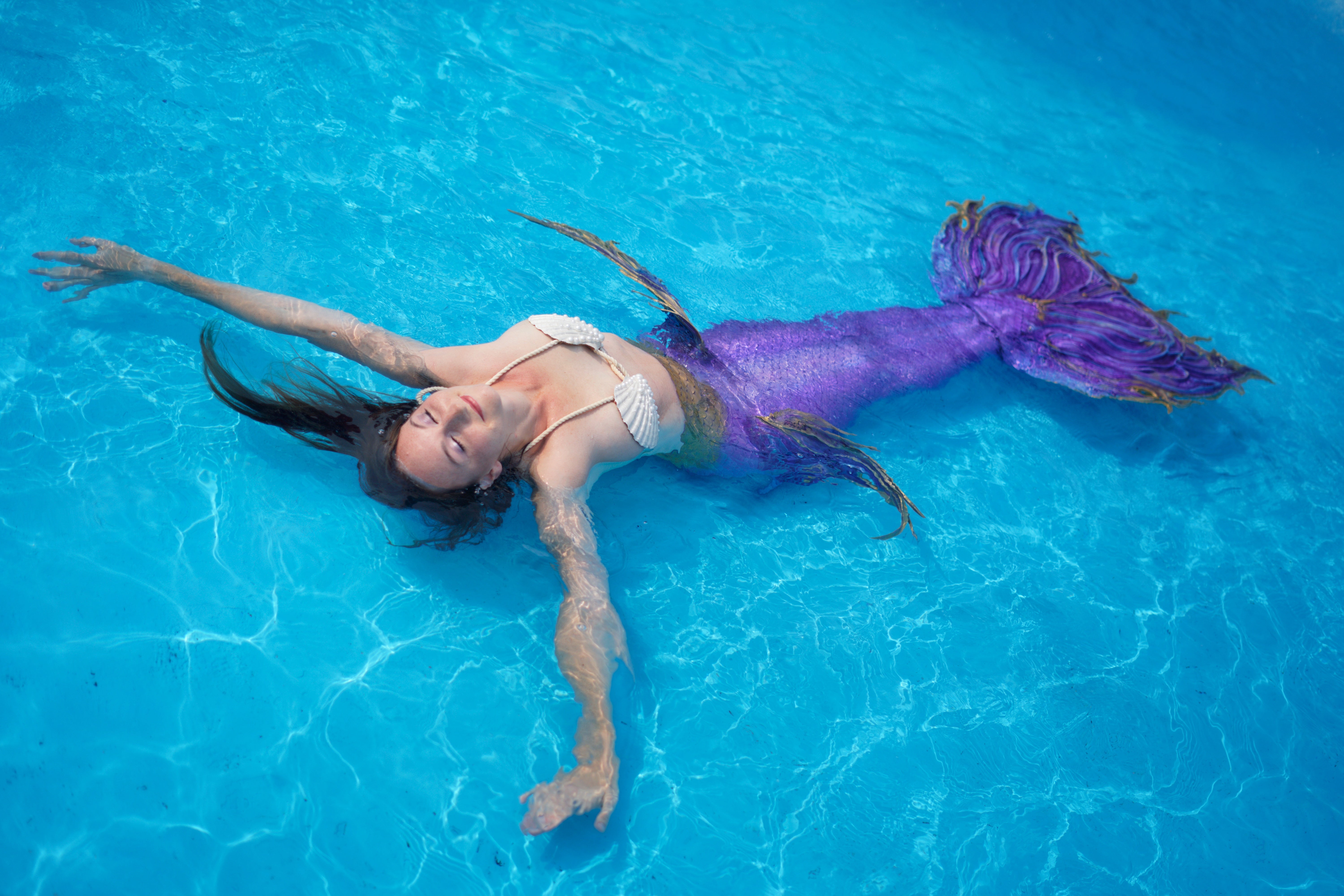 Mermaid performer floating in pool in Miami